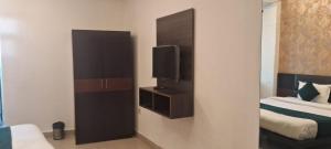 Hotel Anmol Palace في غازي آباد: غرفة مع تلفزيون وسرير وغرفة مع سيد السرير