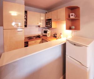 a kitchen with a white refrigerator and wooden cabinets at Le Kervenel - Les Gîtes de la Côte d'Amour in Le Croisic