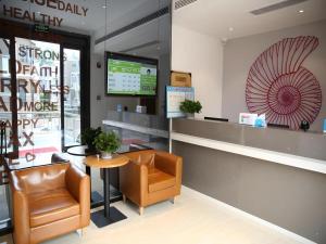 a waiting area of a pharmacy with a chair and a table at Shell Nanjing Jiangning District University City Hotel in Chunhua