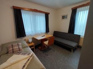Un dormitorio con una cama, un escritorio y un sofá. en Pension Waldfrieden, en Steinhaus am Semmering