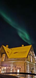 ein Haus mit den grünen Nordlichtern am Himmel in der Unterkunft Vårsol Overnatting i Vardø centrum in Vardø + 5 Fotos