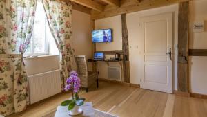 バン・レ・バンにあるChambre Printanière, Maison d'hôtes La Landreのテレビと紫色の花が飾られたテーブルのあるリビングルーム