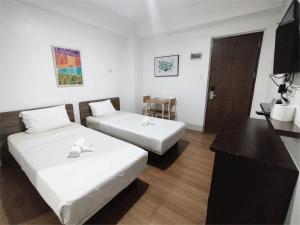 a hotel room with two beds and a table at Sulit Hotel Manila in Manila