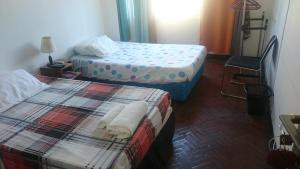 um quarto de hotel com duas camas e uma cadeira em The Quiet Corner Guest House em Maputo