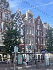 Personas sentadas en una parada de autobús frente a un edificio. en New V, en Ámsterdam