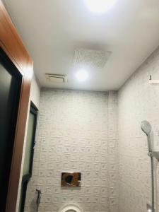 een badkamer met een toilet en een witte muur bij Luxury Manzil in Lahore