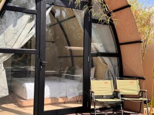 una veranda riparata con 2 sedie e un letto di Nadi Glamping Suites a Perai