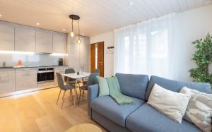 a living room with a blue couch and a kitchen at Mountain view with balcony and free parking in Lungern