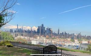 a park bench with a view of a city at Comfy apt with skyline front view Mins away from NYC in Jersey City