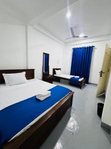Un dormitorio con dos camas con sábanas azules y un azul en Trinco Hybrid Comfort Inn, en Trincomalee