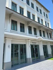 a large white building with green doors at TUAN Hotel Bangkok near Wat Arun in Bangkok Yai