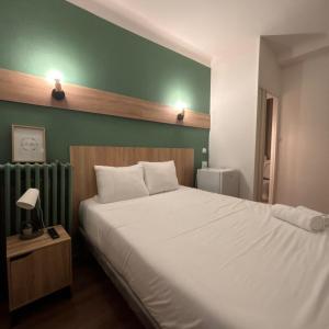 a bedroom with a white bed and a green wall at Central Hôtel in Saint-Priest