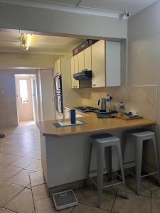 a kitchen with a counter and two stools in it at Tesco Accommodation in Gqeberha