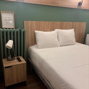 a bedroom with a white bed and a green wall at Central Hôtel in Saint-Priest