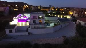 ein großes weißes Haus mit lila Lichtern drauf in der Unterkunft Appartamenti Addimuru in Marina di Palma