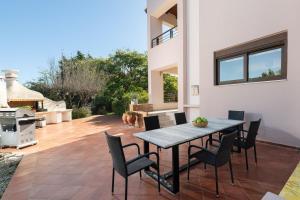 een terras met een tafel en stoelen en een barbecue bij Coral Tree Luxury Villa in Ialyssos