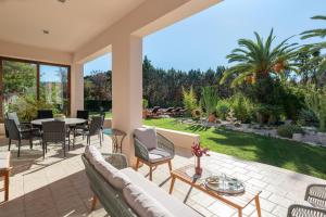 een buitenterras met een tafel en stoelen bij Coral Tree Luxury Villa in Ialyssos