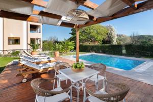 een terras met een tafel en stoelen en een zwembad bij Coral Tree Luxury Villa in Ialyssos