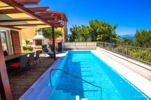 a swimming pool with a table and chairs next to a house at Villa Big View in Splitska