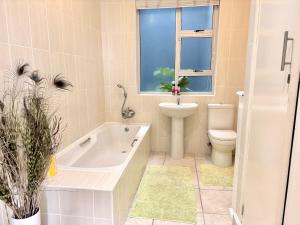 a bathroom with a tub and a toilet and a window at Sunrise & Sunset Haven in Mossel Bay