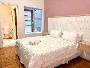 a bedroom with a white bed with a towel on it at Sunrise & Sunset Haven in Mossel Bay +5 photos