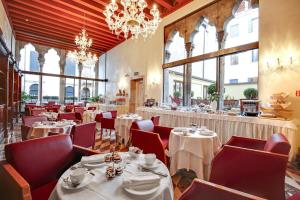 a restaurant with white tables and red chairs at Hotel Donà Palace in Venice