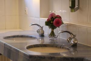 a bathroom sink with two sinks and a vase of flowers at Hotel Sollner Hof in Munich