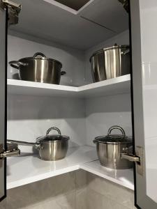 three metal pots sitting on shelves in a kitchen at Leanitai luxury 1-BR Apartment-203 at Qatif شقة فاخرة بغرفة نوم واحدة in Tārūt