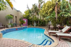 a swimming pool with two lounge chairs and a house at Kingfisher GuestHouse in Port Elizabeth