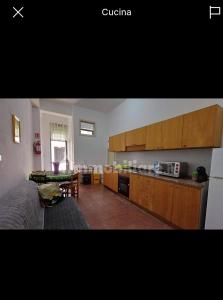 a kitchen with wooden cabinets and a living room at Florina Appartment in Capo dʼOrlando