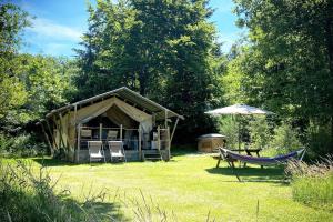 a tent with chairs and a hammock in a yard at Le Ranch Camping et Glamping in Madranges