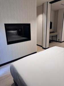 ein Schlafzimmer mit einem Bett und einem Fernseher an der Wand in der Unterkunft Luxury Studio, 1 Bed, Separate Study Gourmet Kitchen Prime Location in Bangalore