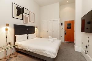 een slaapkamer met een groot wit bed en een glazen tafel bij Kensington House Hotel in Londen