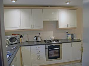 een keuken met witte kasten en een kookplaat oven bij 2 Bed in Birnam CA266 in Birnam