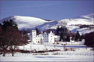 Een groot wit gebouw in de sneeuw met bergen op de achtergrond. bij 2 Bed in Birnam CA266 in Birnam +11 foto's
