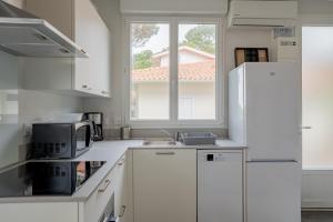 a white kitchen with a microwave and a sink at Villa Germaine les pieds dans l'eau in Andernos-les-Bains