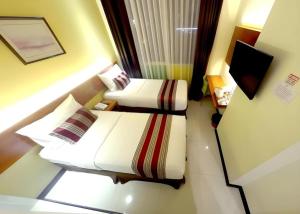ein kleines Zimmer mit zwei Betten und einem Fernseher in der Unterkunft Biz Boulevard Hotel in Manado