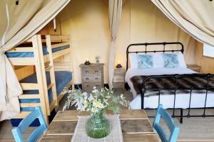 a bedroom with two bunk beds and a table at Le Ranch Camping et Glamping in Madranges