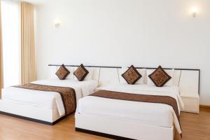 two beds in a room with white walls and wood floors at K-BOSS Hotel in Bắc Ninh