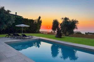 una piscina con due sedie e un ombrellone di Villa Cypressa by Villa Plus a Kalamitsi