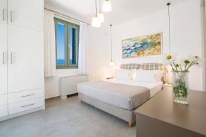 una camera bianca con un letto e un vaso di fiori di Villa Cypressa by Villa Plus a Kalamitsi Altre 10 foto