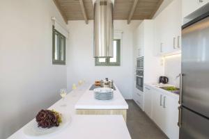 una cucina bianca con un bancone con bicchieri di vino di Villa Cypressa by Villa Plus a Kalamitsi