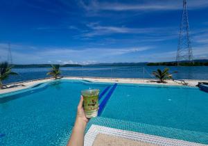 una persona sosteniendo una bebida frente a una piscina en MNResort, en Koh Kong