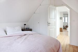 a white bedroom with a bed and an open door at Kembser Kate - Ostholstein - NEU! in Behrensdorf