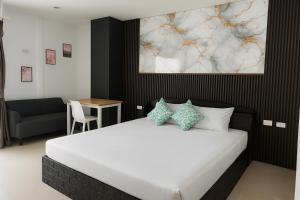 Happy Fish Guesthouse في شاطيء باتونغ: غرفة نوم بسرير ابيض وطاولة وكرسي