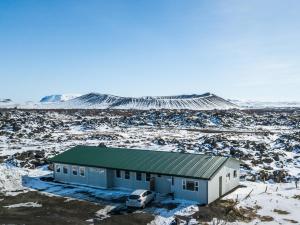 a building with a car parked in a snowy field at Vogar Travel Service in Myvatn