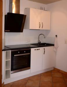 una cucina con mobili bianchi, un lavello e un microonde di Ferienwohnung Dauth a Kressbronn am Bodensee