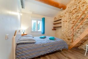 a bedroom with a bed and a stone wall at Chambre Bleuet in Piolenc