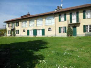 Cascina Barosca في Castelnuovo Don Bosco: مبنى كبير شبابيكه خضراء وبيضاء وساحة