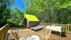 a deck with a green roof and a table and chairs at Logements Insolites, Les Rêves d'Ambre  +29 photos